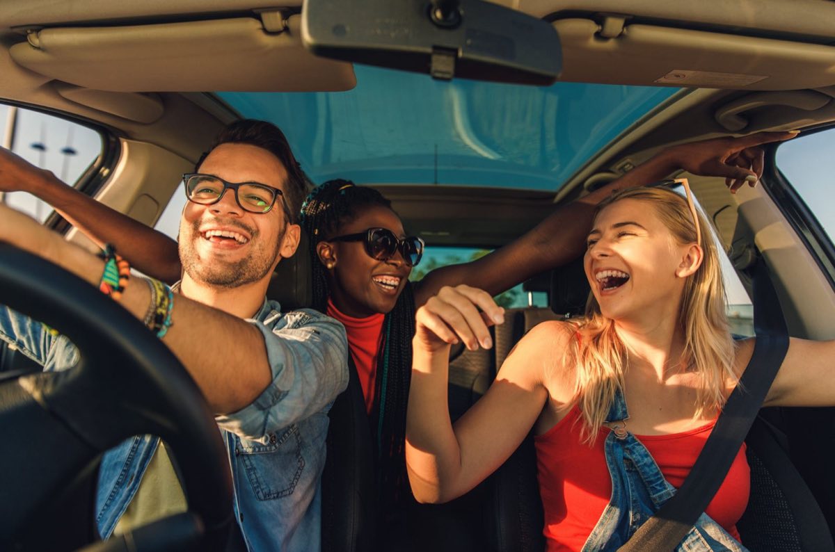 Three friends laughing together on a shared car journey